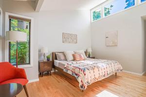 贝尔维尤Sunlit contemporary Bellevue Home w a Lush Garden的一间卧室配有一张床、一把椅子和窗户。
