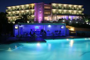 毕达哥利翁普林赛萨里维埃拉度假酒店的一座游泳池,在晚上在建筑物前