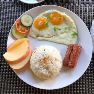 班塔延岛Anahaw Seaside Inn的鸡蛋米饭和蔬菜的白盘食物