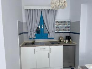 弗伊尼基昂GIAVASI SEASIDE FINIKI的厨房配有白色橱柜和蓝色窗户。