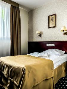 鲁达希隆斯卡Hotel Adria的酒店客房,配有一张带金色毯子的床