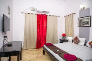 马普萨RONNE'S VILLA De SOL-3BHK LUXURY VILLA In Assagaon的一间卧室配有一张带红色窗帘的床和一张书桌