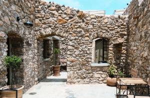 PírgosPyrgi Cretan Living & Spa的一座带拱门和桌椅的石头建筑
