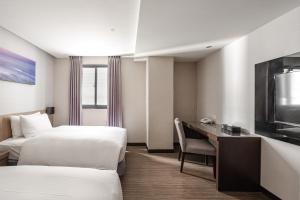 高雄佑煦行旅的酒店客房设有两张床、一张桌子和一台电视。
