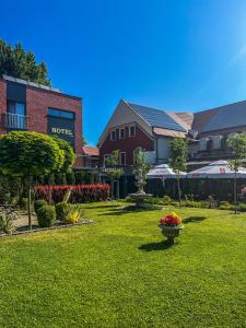 鲁达希隆斯卡Hotel Adria的一座绿色庭院,在院子里有房子和鲜花