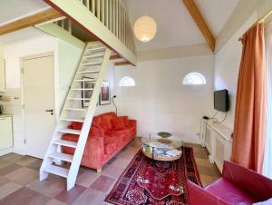 伊皮Uylkenshof safaritenten en natuurhuisjes的一间带楼梯和红色沙发的客厅