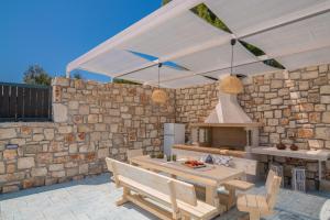 瓦西里科斯Le Mar Villa的室外厨房设有石墙和白色的天篷