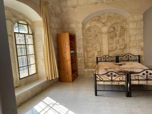 伯利恒Dar Ateeq's Arches/ Bethlehem Apartment的一间卧室设有一张床和两个窗户。