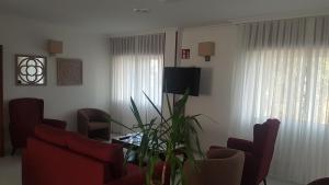 波多诺伏旁塔斯姆酒店的客厅配有红色椅子和植物桌子