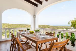 马翁Villa Cala Llonga的阳台的用餐室配有桌椅