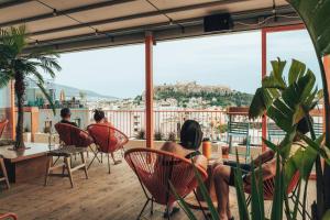雅典Selina Athens Theatrou的一群人坐在阳台上的椅子上