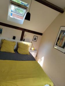 巴黎Atelier d'artiste - Loft with garden center of Paris的一间卧室配有一张带黄色枕头的床和一扇窗户
