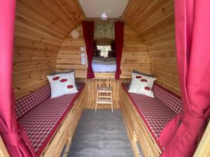 FriedersbachAndrella Auszeithof - Schlaferlebnis im Holzfass的小木屋内带两张床铺和红色窗帘的房间