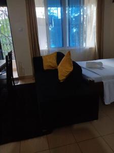 姆特瓦帕Mkombodzi Global Homes的一张带黄色枕头的黑椅,就坐在床边