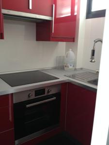 英格兰海滩Apartamento Paco的厨房配有红色橱柜和黑色烤箱