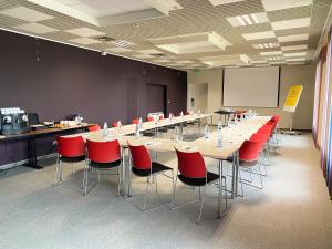 科尔马科尔马北宜必思尚品酒店的一间会议室,配有长桌子和红色椅子