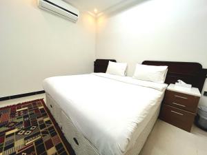 苏尔Al Taraf Hotel Apartment的一间卧室配有一张带白色床单的大床