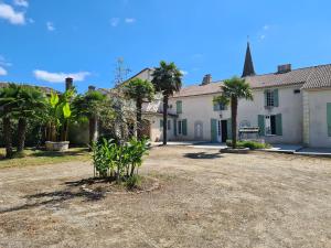 SoubranL'hacienda de Soubran, Le Gîte à Grand-mère, classé 4 étoiles的前面有棕榈树的房子