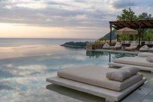 阿吉奥斯伊欧尼斯阿加皮托斯别墅宾馆的一个带躺椅的游泳池和海洋