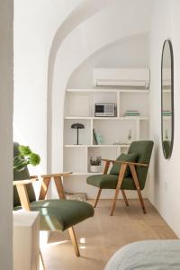 卢布尔雅那April1550 Boutique Hotel的一间设有两张绿色椅子和一张桌子的房间