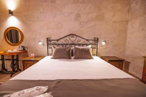 于尔居普Canyon Cave Hotel的卧室配有一张带白色床单和枕头的大床。