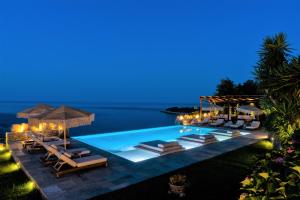 阿吉奥斯伊欧尼斯阿加皮托斯别墅宾馆的夜间带躺椅和遮阳伞的游泳池