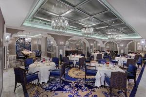 新德里ITC Maurya, a Luxury Collection Hotel, New Delhi的用餐室配有桌椅和吊灯。