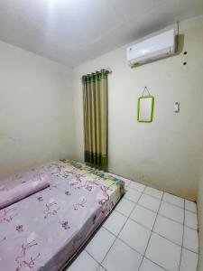 马格朗Anindya House的一间卧室配有一张带粉色床单的床和一扇窗户。
