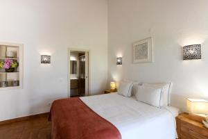 卡巴纳斯·德·塔维拉佩德拉达赖尼亚度假村的卧室配有一张白色大床,墙上有灯