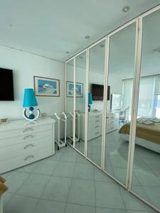 伊斯基亚Hotel Solemar Beach & Beauty SPA的一间带镜子、一张床和电视的卧室