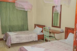 内罗毕KAP Guest House的一间设有两张床、一张桌子和一把椅子的房间