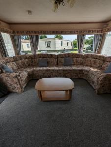 达农30 Glenfinart Caravan Park的客厅配有大沙发和桌子