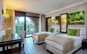 马尔马里斯Marmaris Bay Resort - Adults Only的酒店客房设有两张床、一张桌子和一张桌子。