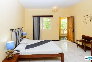 马哈赞加马任加可可酒店及餐厅的一间卧室配有一张大床和一架钢琴