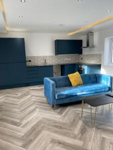 斯旺西Walter Road Holiday Home Swansea - 4 bedrooms的客厅设有蓝色沙发,配有厨房