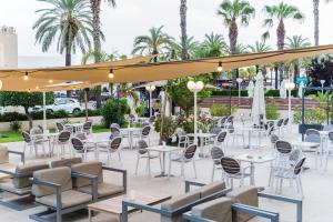 萨洛普拉纳斯酒店的庭院配有白色桌椅,棕榈树