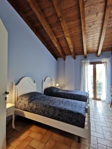 Luci nel Bosco的卧室设有两张床,拥有蓝色的墙壁和木制天花板
