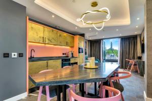 爱丁堡Roomzzz Edinburgh的厨房配有木桌和粉红色的椅子