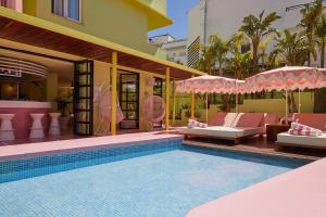 普拉亚登博萨Tropicana Ibiza Suites - Adults Only的一座带椅子和遮阳伞的游泳池位于一座建筑旁边