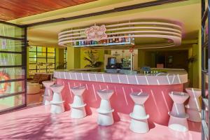 普拉亚登博萨Tropicana Ibiza Suites - Adults Only的餐厅设有粉红色的柜台和白色的椅子