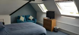 卡菲利Ty Castell Guest House的一间卧室配有一张床、一台电视和一把椅子