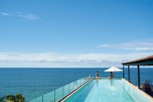 蓬塔米塔Hotel Basalto的两人坐在游泳池边,俯瞰大海
