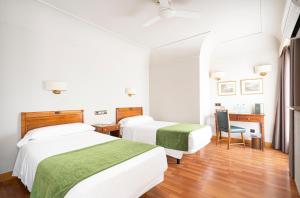 希洪埃尔南科尔特斯酒店的一间卧室配有两张床、一张桌子和一把椅子