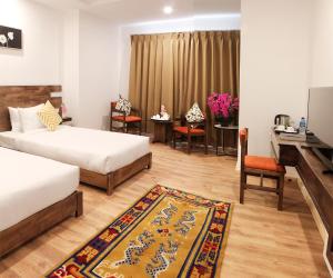 廷布Hotel Mayto的酒店客房带两张床和一张桌子以及椅子。