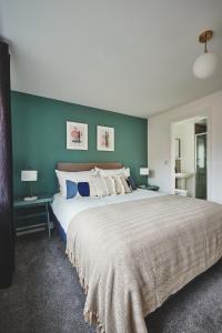 CanleyCoventry Home for 6+2, 150Mbp Wi-Fi + Parking的一间卧室配有一张带蓝色墙壁的大床