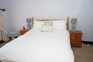 沙夫茨伯里Character 2 double bedroom cottage in Shaftesbury的卧室配有白色床、两盏灯和一把椅子
