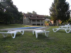 Casa rural con piscina的坐在房子前面的草上,三个白长椅