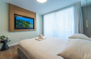 埃拉特Sea side "Tulip" apartment - by Rently的一间卧室设有一张大床和一台墙上的电视。