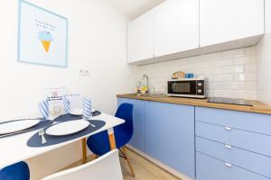 巴拉顿诺尔马迪Balaton Wave Apartments的厨房配有蓝色的椅子和一张带微波炉的桌子。