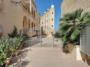 MġarrEast Breeze Penthouse的一座楼旁的棕榈树门